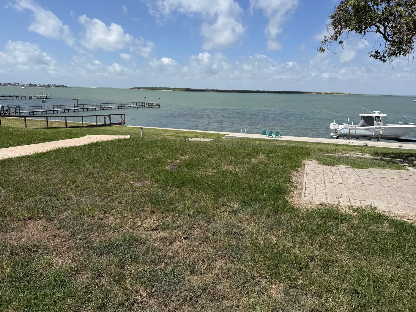 A bayfront lawn running down to a private pier and boat