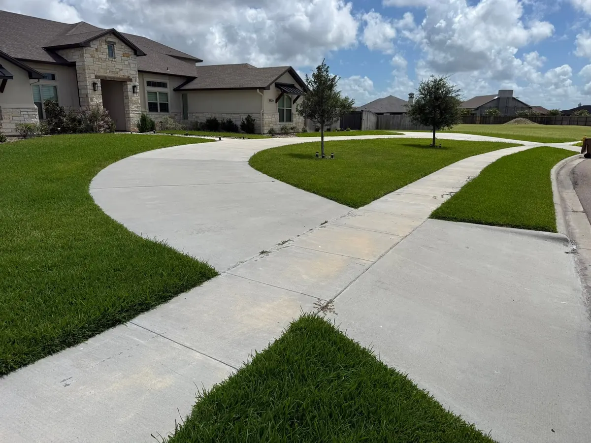 Two concrete walkways meeting with sharply edged turf on every side